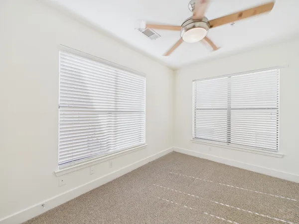 an empty room with a window and ceiling fan