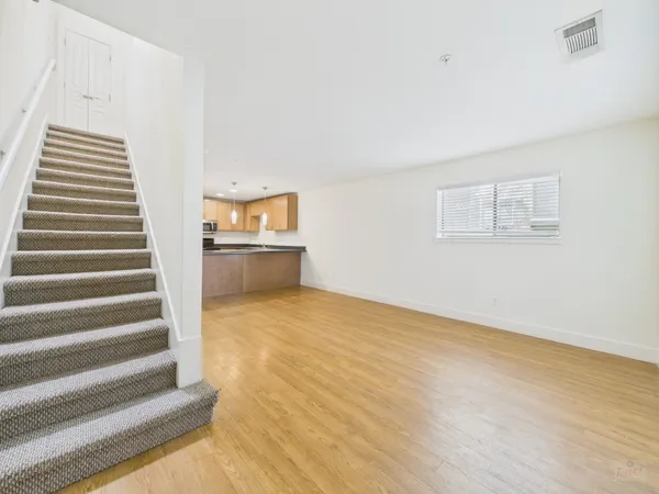 a view of an empty room with wooden floor and stairs