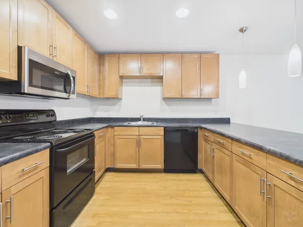 a kitchen with stainless steel appliances granite countertop a stove a sink and a microwave