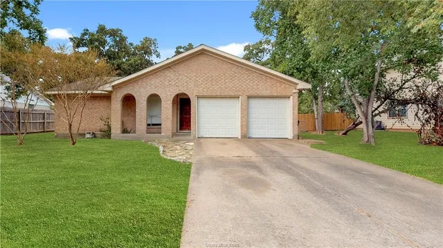 a view of a yard in front of a house with large trees
