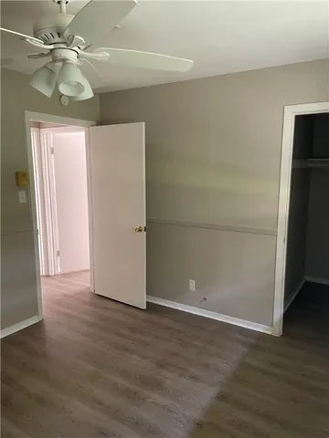 an empty room with wooden floor and ceiling fan
