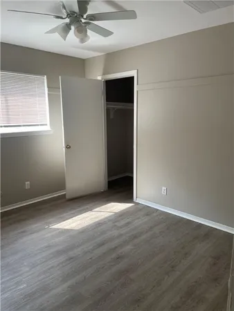 an empty room with wooden floor closet and windows