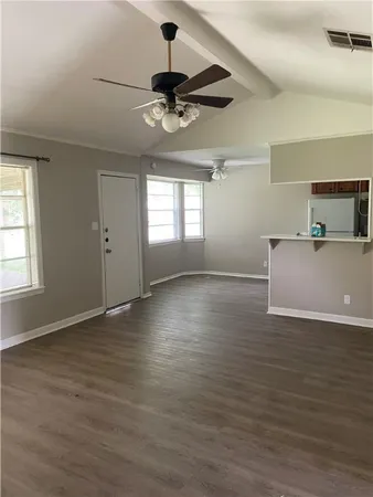 a view of an empty room with window and wooden floor