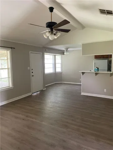 a view of an empty room with window and wooden floor