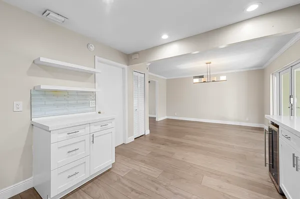 a view of an empty room with wooden floor ceiling fan