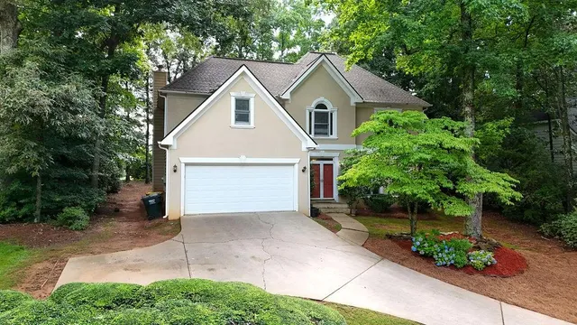 a view of a white house next to a yard and large trees