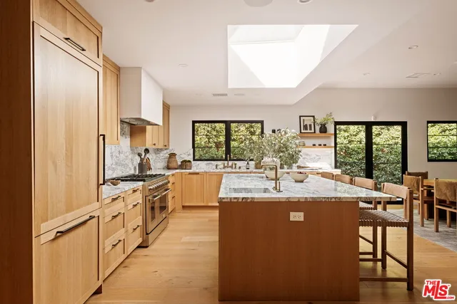 a large kitchen with kitchen island a large counter top space a sink a stove and a refrigerator