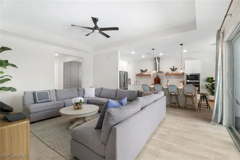 a large white kitchen with a stove a sink a kitchen island with chairs and wooden floor