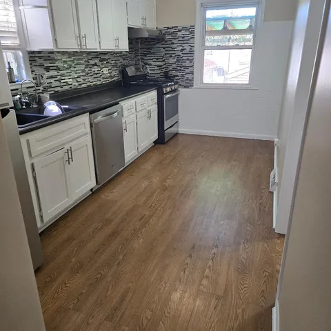 a kitchen with granite countertop a sink cabinets and wooden floor