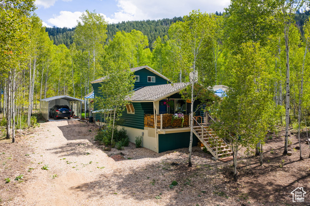 714 Spotted Fawn Way Kamas, UT 84036 - Photo 30 of 34 View of front facade with a porch, dirt driveway, a forest view, and a carport