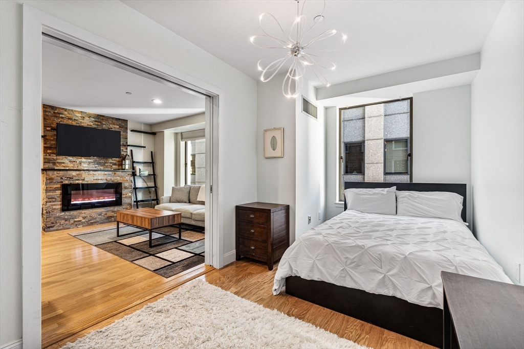 80 Broad Street, Unit 805 Boston, MA 02110 - Photo 12 of 22 a bedroom with a large bed and a chandelier