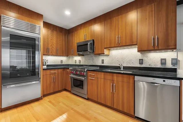 a kitchen with stainless steel appliances granite countertop wooden cabinets a stove top oven a sink and dishwasher