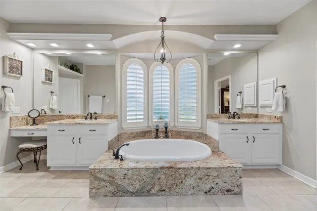 a bathroom with a granite countertop sink a large mirror and a bathtub