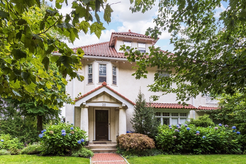 a front view of a house with a yard and potted plants