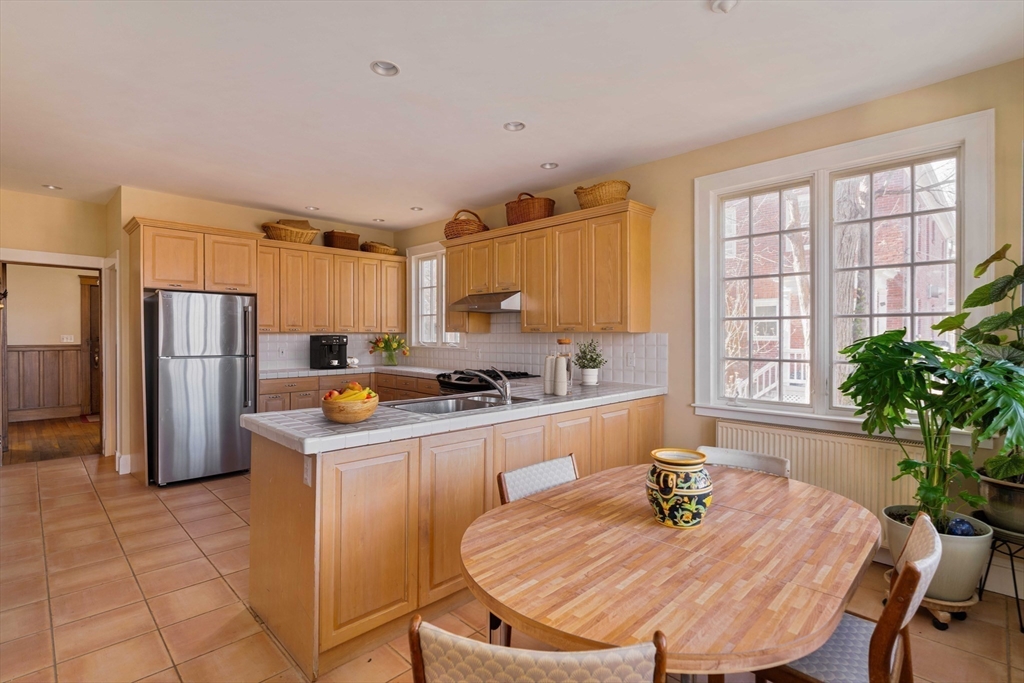 289 Clinton Road Brookline, MA 02445 - Photo 3 of 24 a kitchen with stainless steel appliances granite countertop a refrigerator a stove a sink a dining table and chairs