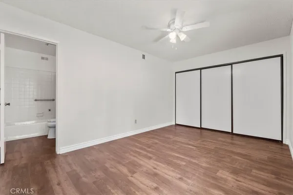 an empty room with wooden floor and a ceiling fan