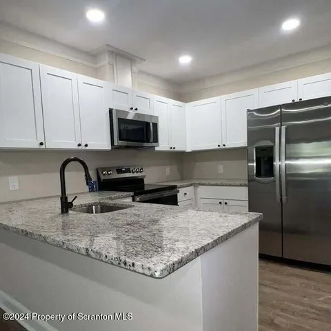 a kitchen with granite countertop a sink and a stove top oven with wooden floor