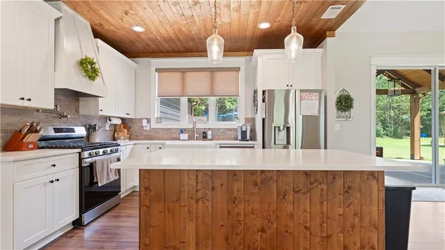 a kitchen with stainless steel appliances granite countertop a stove a sink dishwasher and a refrigerator with wooden floor