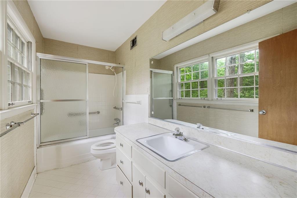 1911 Alderbrook Road Northeast Atlanta, GA 30345 - Photo 28 of 33 a bathroom with a granite countertop sink a large mirror a toilet and shower