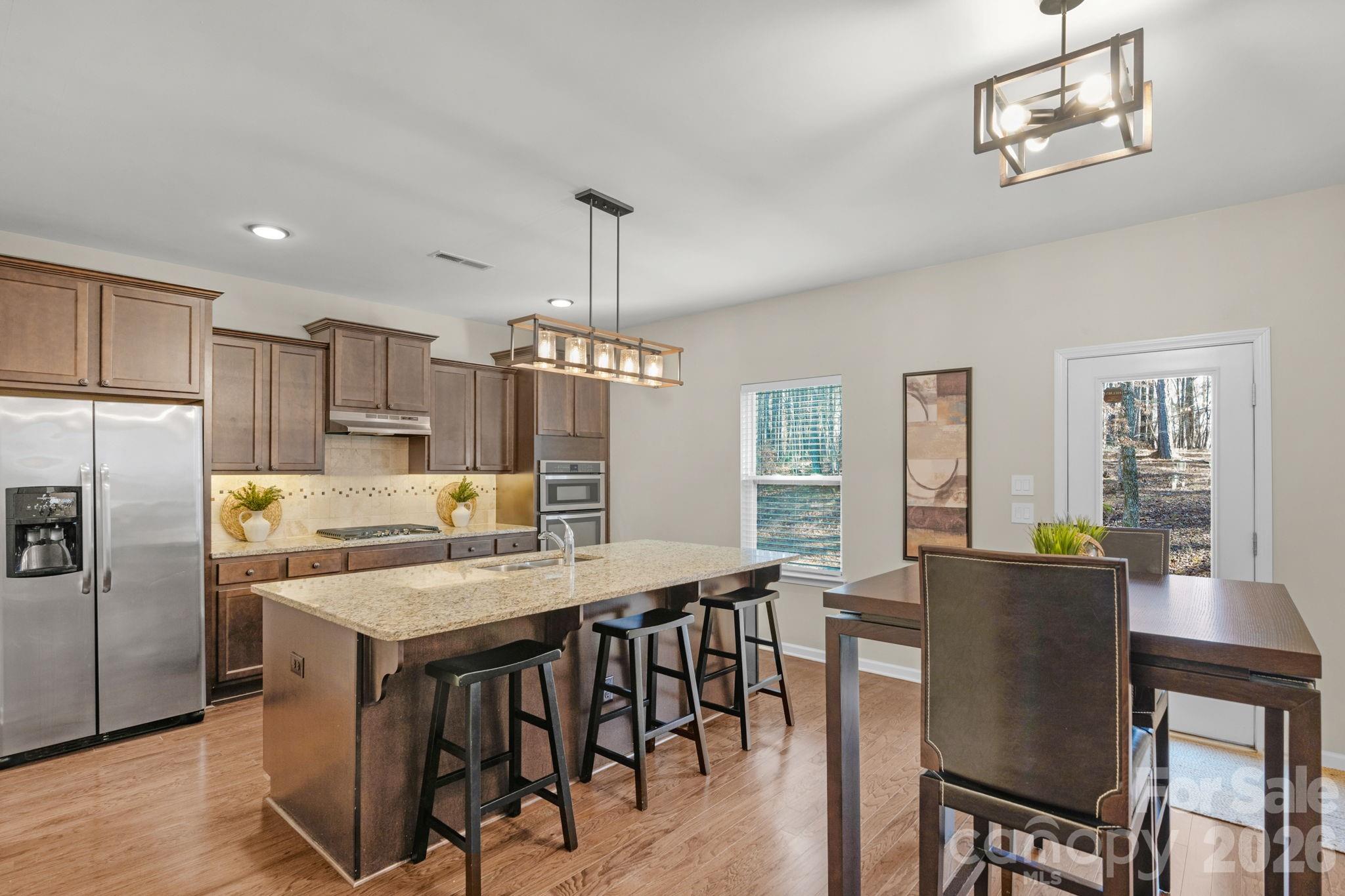 1508 Springfield Drive Waxhaw, NC 28173 - Photo 16 of 48 a kitchen with stainless steel appliances granite countertop a dining table chairs refrigerator and cabinets