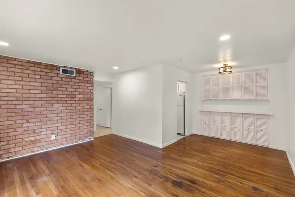a view of empty room with wooden floor and windows