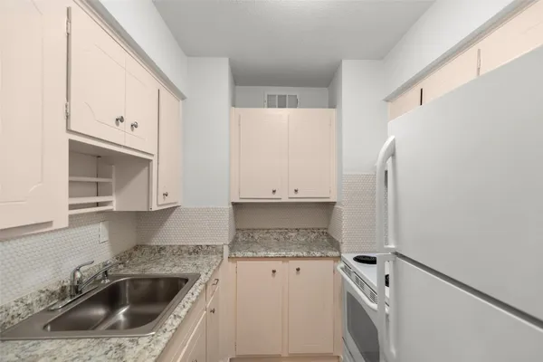 a kitchen with granite countertop a sink stove and cabinets