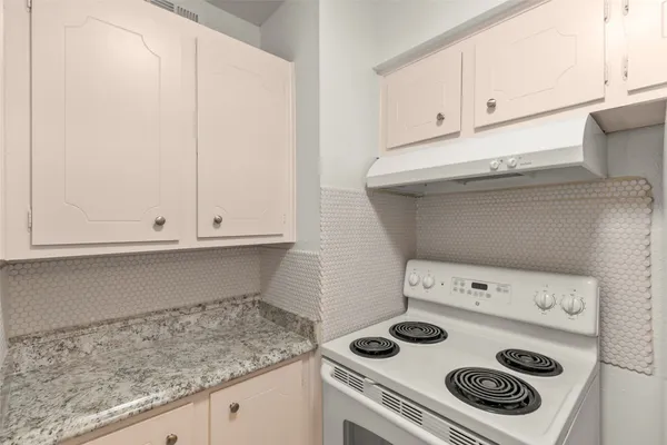 a kitchen with a stove and white cabinets
