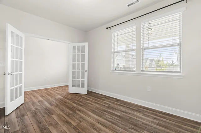 a view of an empty room with wooden floor and a window