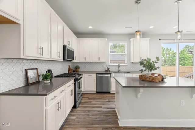 a kitchen with stainless steel appliances a dining table chairs and wooden floor