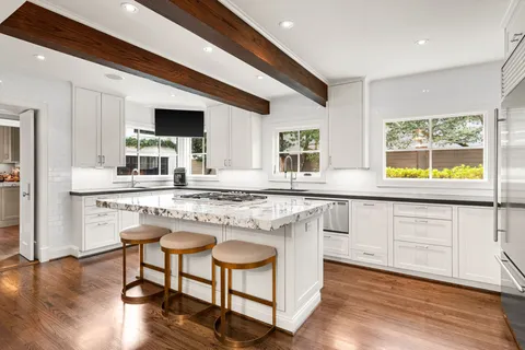 a kitchen with stainless steel appliances granite countertop wooden floor a stove a sink a refrigerator dining table and chairs