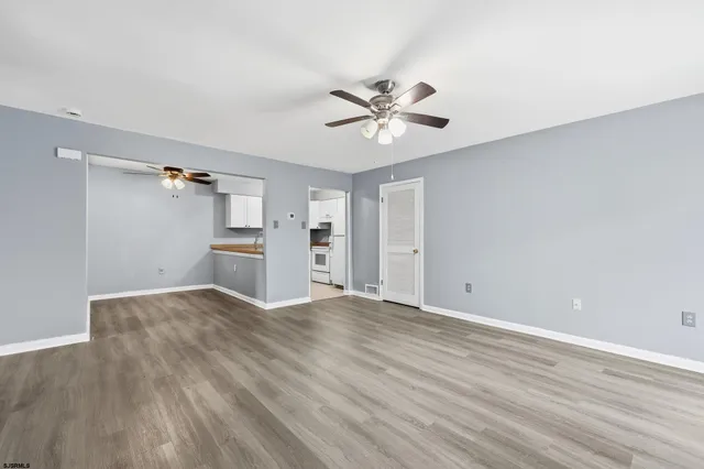 an empty room with wooden floor and ceiling fan