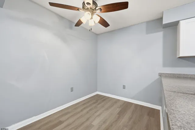an empty room with wooden floor ceiling fan and windows