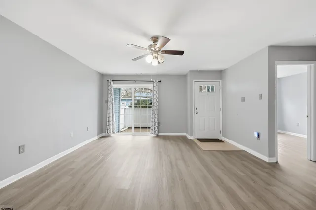 an empty room with wooden floor and ceiling fan