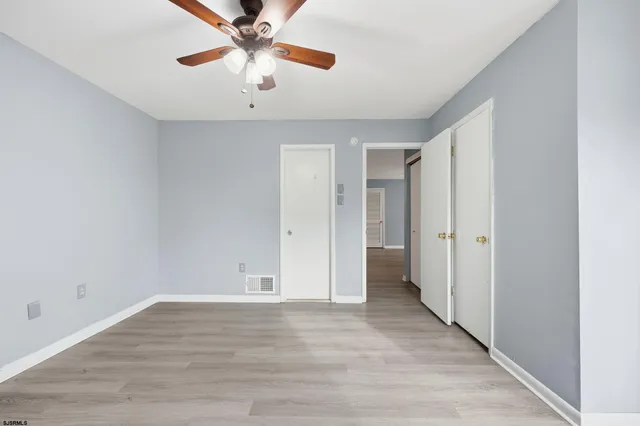 an empty room with wooden floor fan and windows