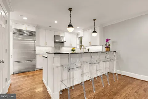 a kitchen with stainless steel appliances granite countertop a stove a sink and a granite counter tops with white cabinets