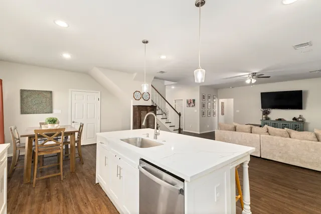 a large white kitchen with a sink and a stove top oven with wooden floor