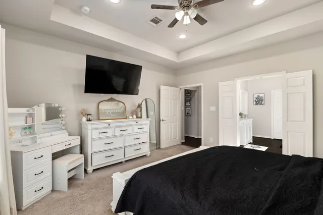 a bedroom with a bed and a flat tv screen on dresser