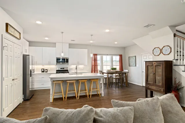 a view of a dining room with furniture a kitchen and chandelier