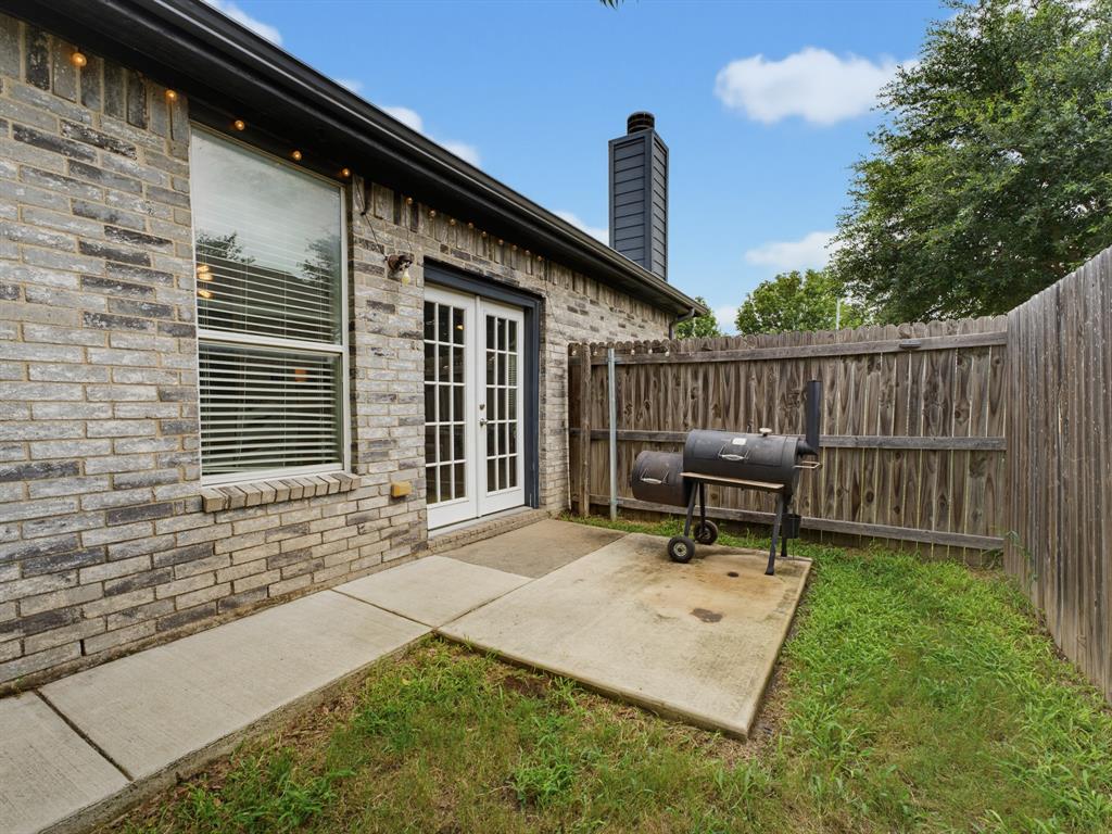 600 Stirling Road Rhome, TX 76078 - Photo 33 of 38 Brick exterior featuring a patio area with a concrete slab, wood privacy fencing, and a modern black chimney