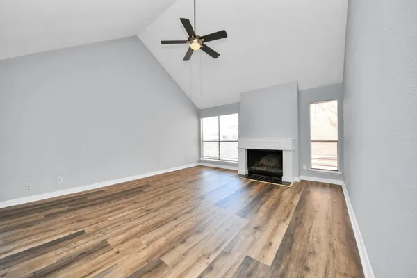 a view of empty room with wooden floor and fan