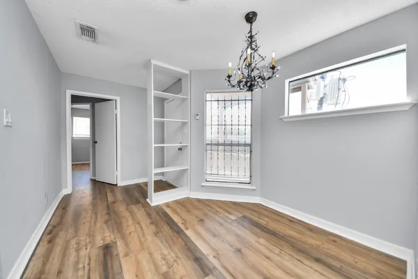 a view of a white house with large trees plants and palm trees