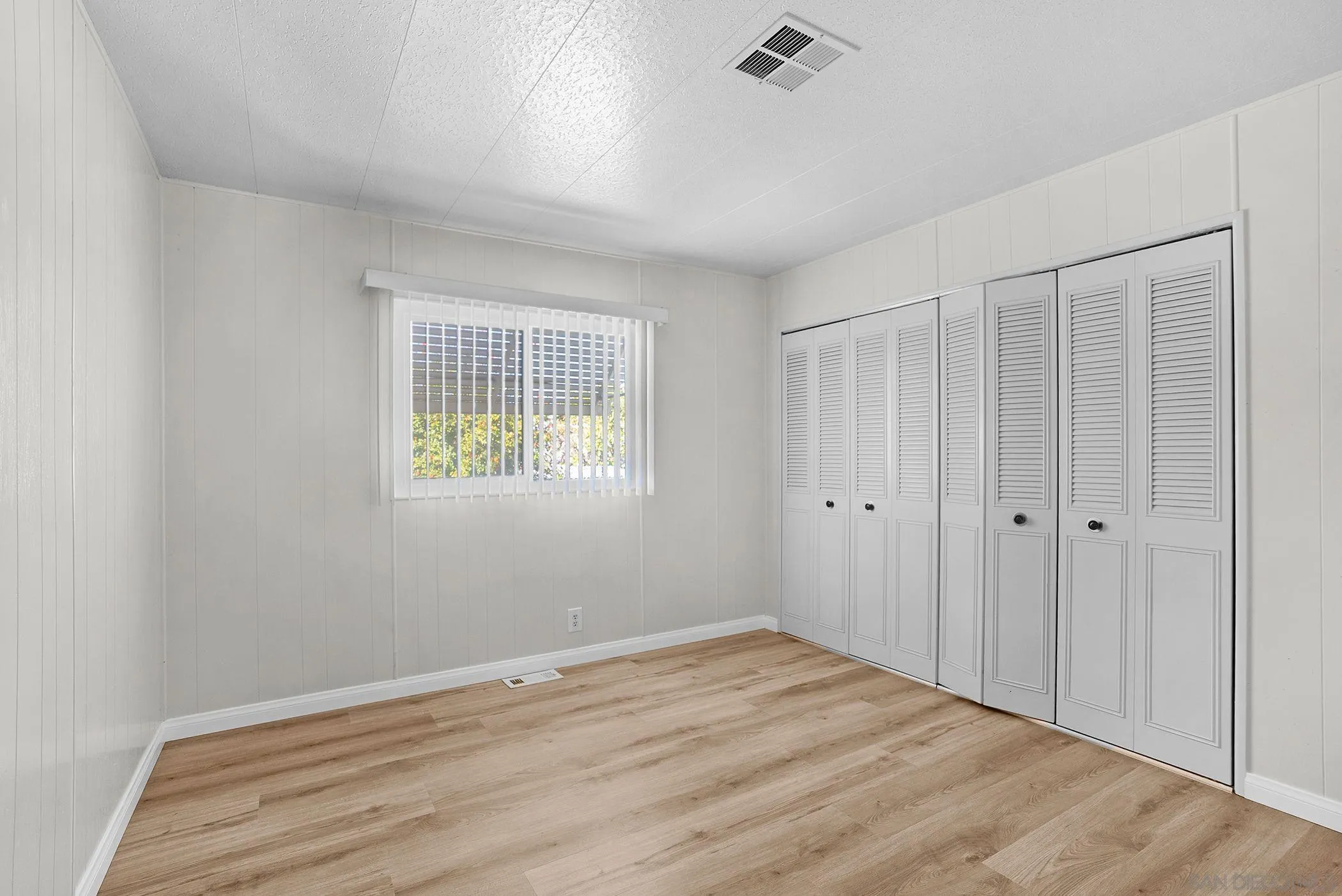 1925 Otay Lakes Road, Unit 167 Chula Vista, CA 91913 - Photo 4 of 11 a view of an empty room with wooden floor and a window