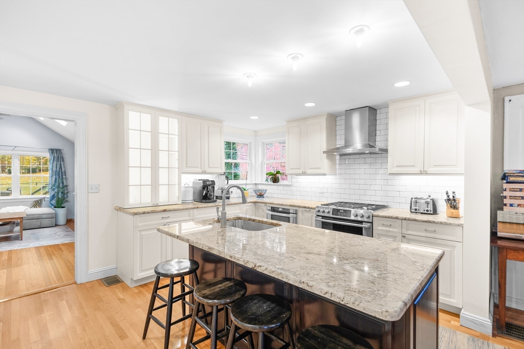 486 Washington Street Walpole, MA 02032 - Photo 5 of 17 a kitchen with stainless steel appliances granite countertop a stove a sink a refrigerator white cabinets and chairs with wooden floor
