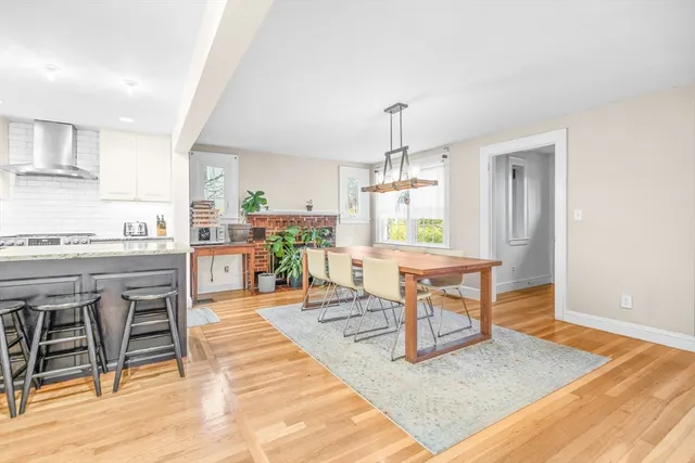 a living room with a dining table wooden floor and a rug
