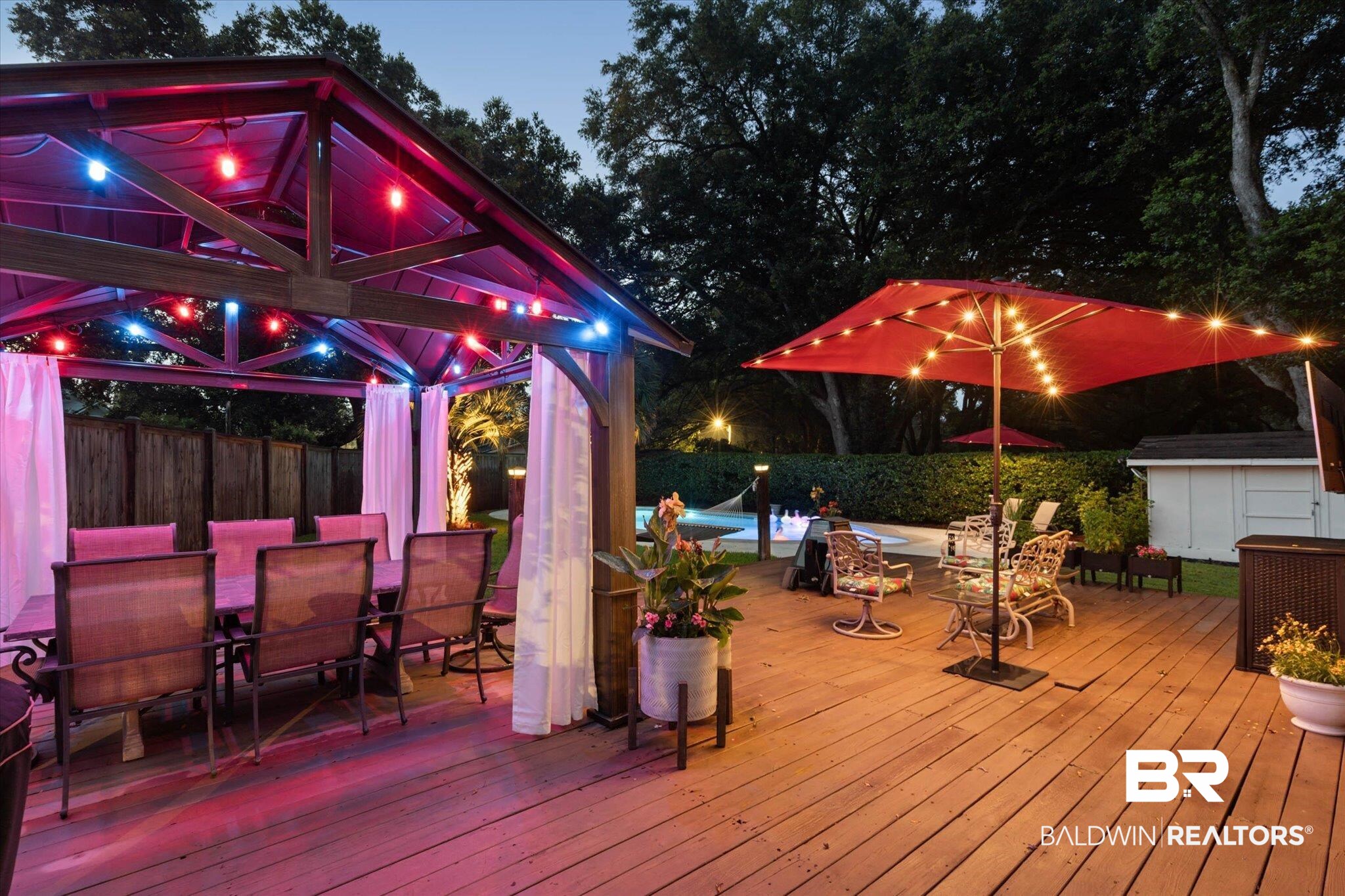 101 Ann Street Daphne, AL 36527 - Photo 36 of 38 Expansive wood-finish deck featuring a covered gazebo with string lighting, a privacy fence, and a swimming pool in the background