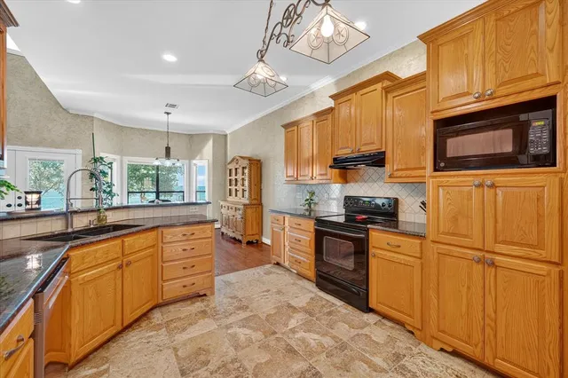 a kitchen with granite countertop a sink stainless steel appliances and cabinets