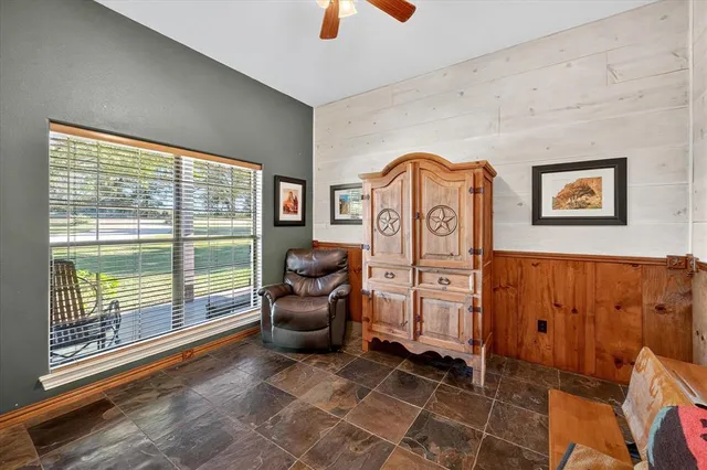 a living room with furniture a flat screen tv and floor to ceiling window