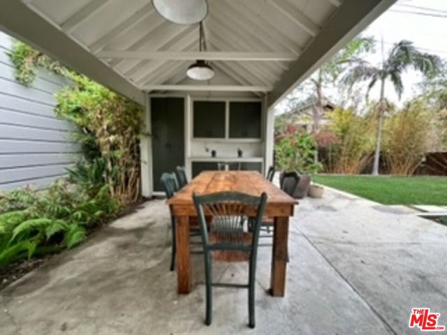 a patio with a table and chairs and potted plants