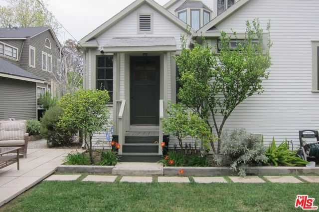 a view of a white house with a small yard and plants