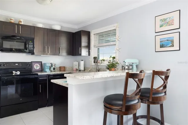 a kitchen with stainless steel appliances granite countertop a stove top oven a sink a dining table and chairs with wooden floor